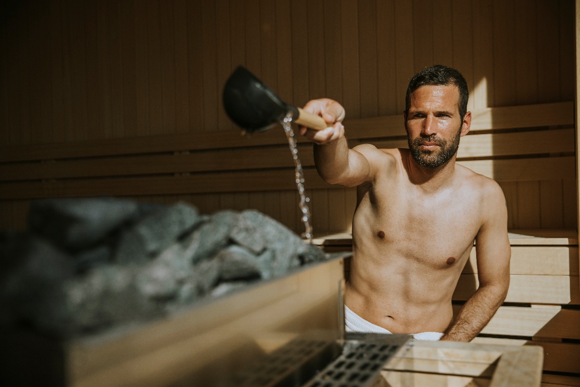 Изливане на вода върху камъните за сауна